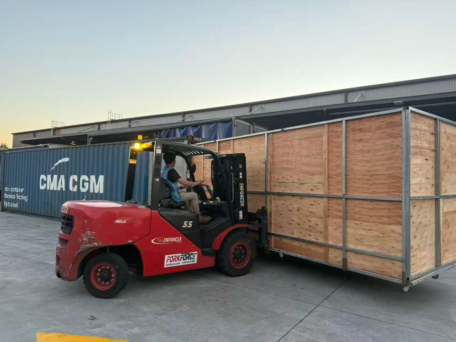 Forklift handling oversized crated cargo for container loading